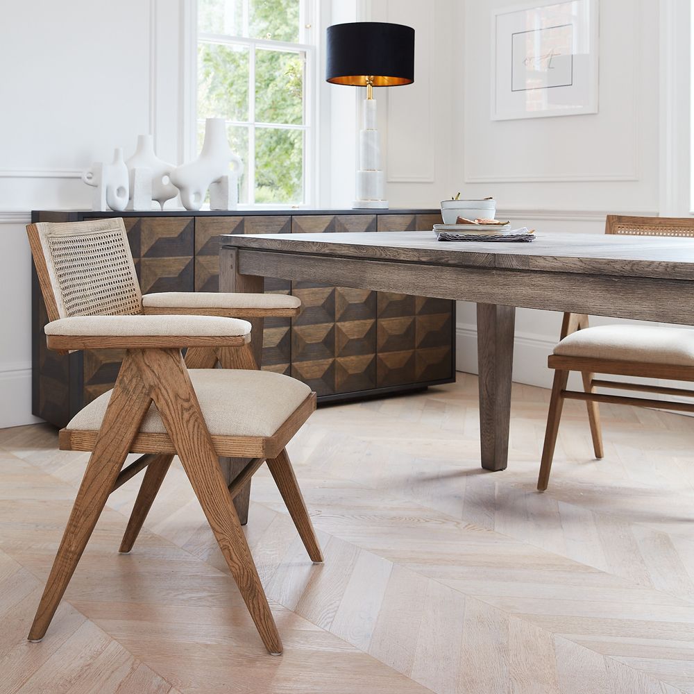 a natural wooden dining table with chairs and a sideboard in the background