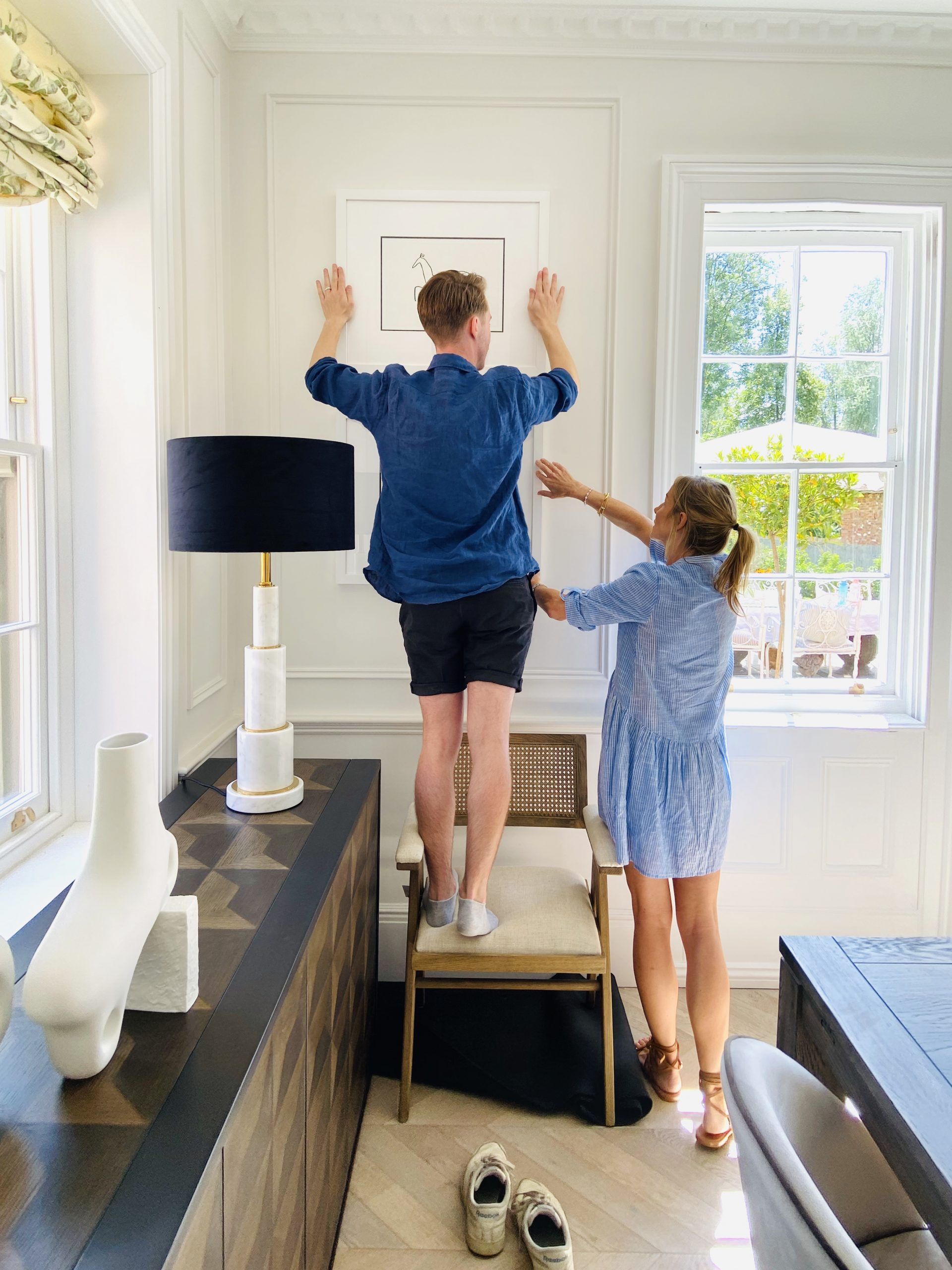 a man and a women putting up wall art