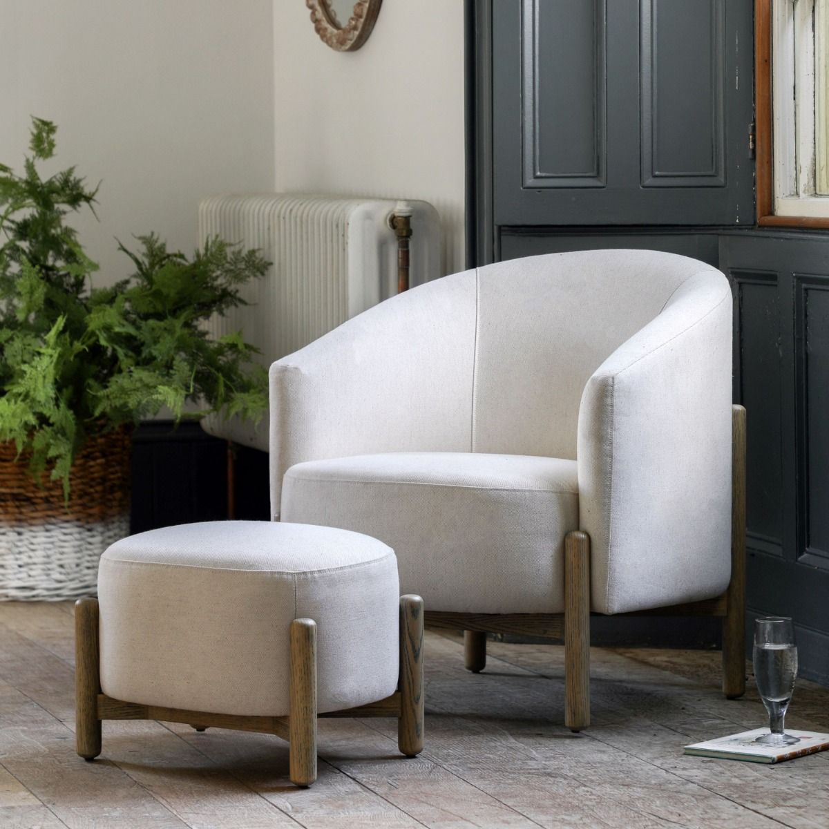 Sumptuous upholstered armchair with curved back and natural wooden legs