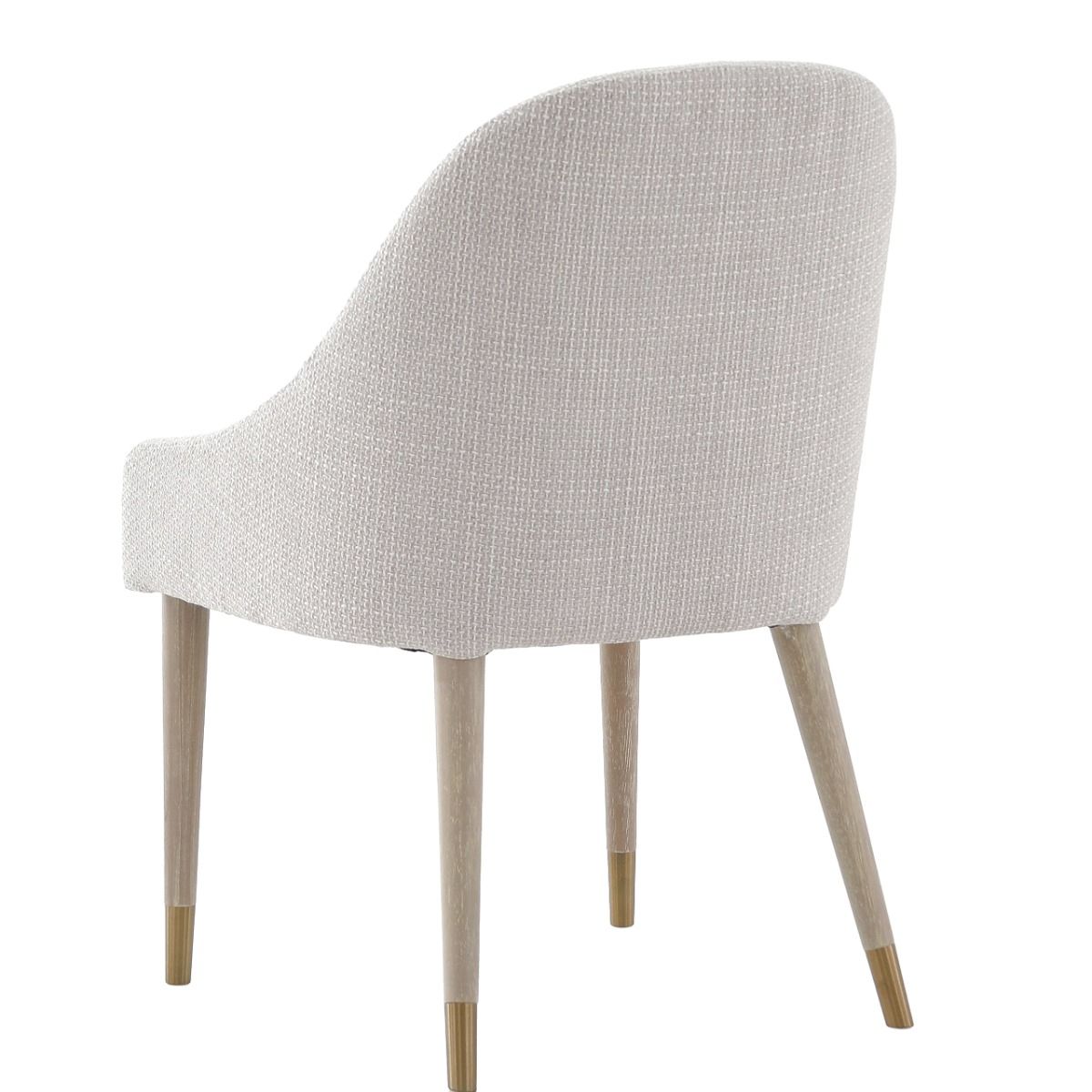 The Bibury Dining Chair features sleek sloped arms, a rounded frame, and solid wood legs with brass golden caps, providing both comfort and style.
