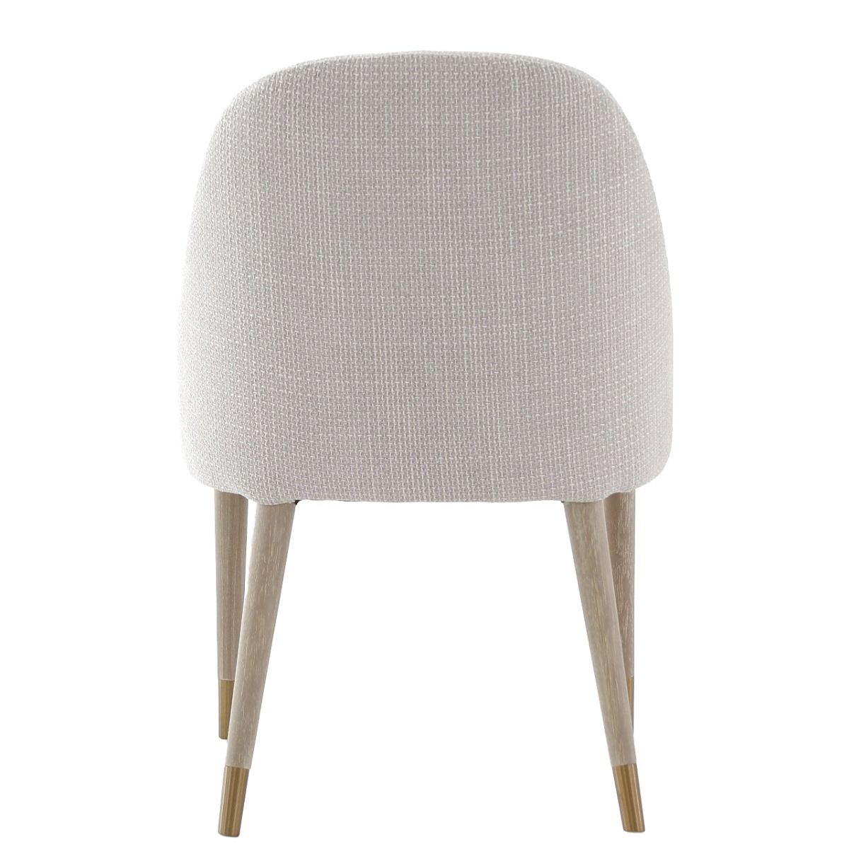 The Bibury Dining Chair features sleek sloped arms, a rounded frame, and solid wood legs with brass golden caps, providing both comfort and style.