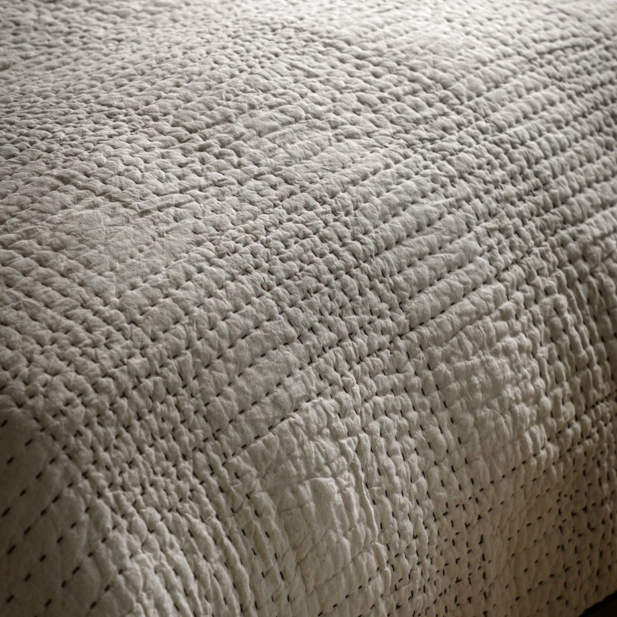 Beige quilted bedspread with black stitching