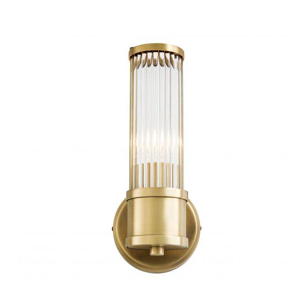 A glamorous wall lamp with an antiqued brass finish and reeded glass
