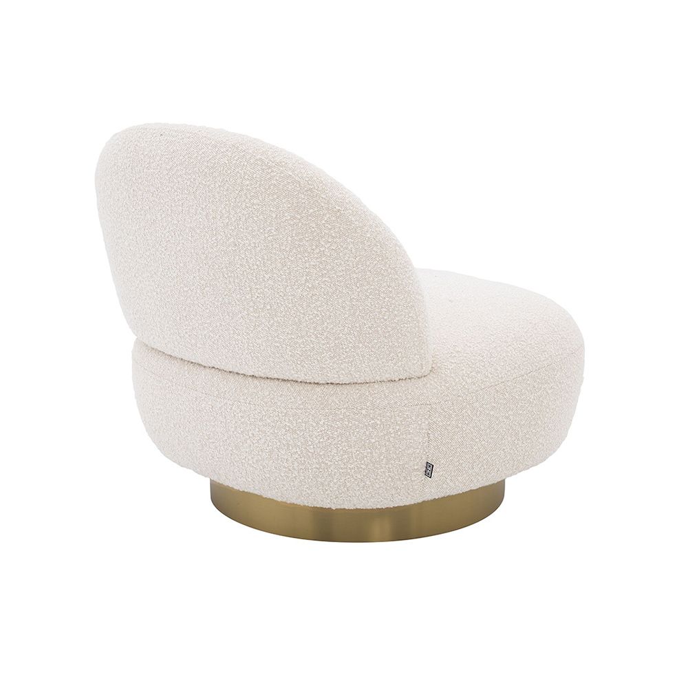 A luxurious boucle armchair with a brushed brass swivel base