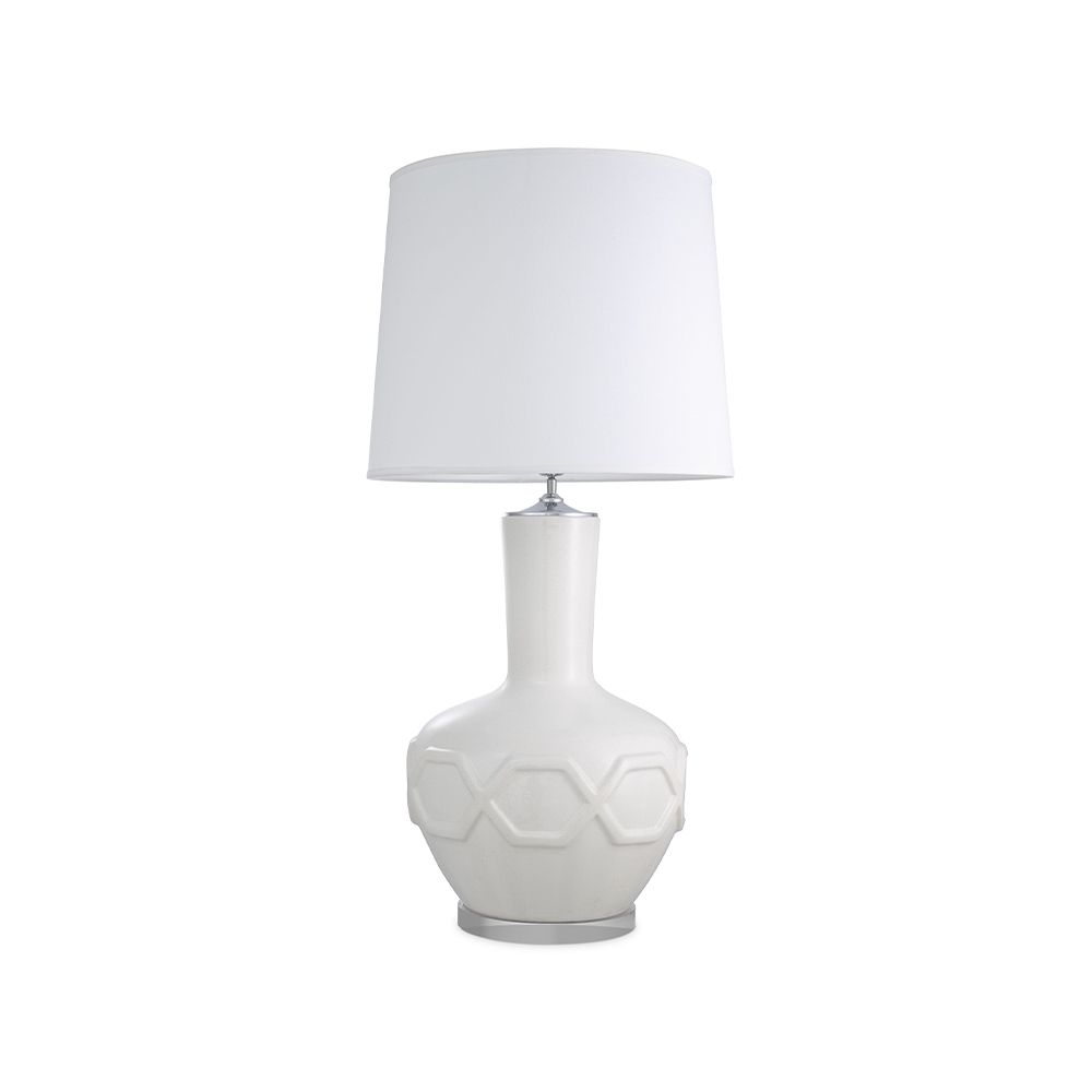 A stylish table lamp by Eichholtz with a white porcelain base featuring relief patterns, a crystal glass plinth and off-white fabric shade