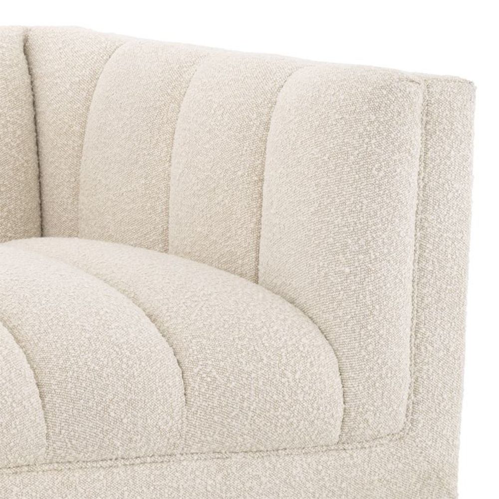 A luxurious lounge sofa by Eichholtz with a bouclé cream upholstery, deep channel stitching and a black base