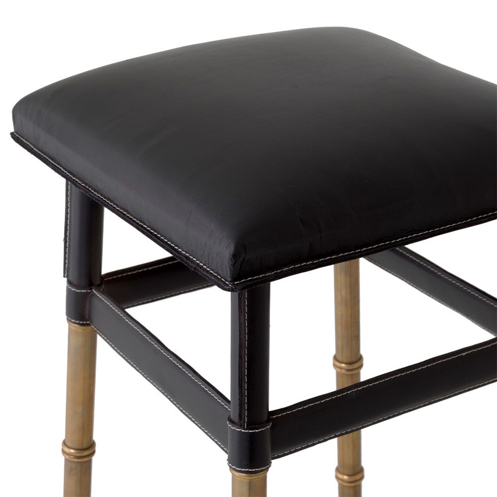 A stylish bar stool by Eichholtz with a black leather and vintage brass finish