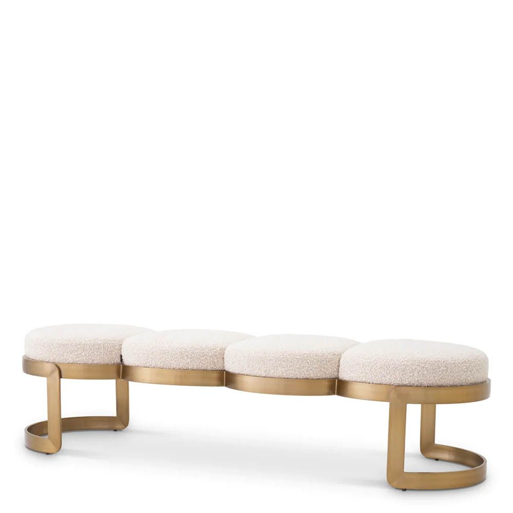 A luxury bench by Eichholtz with a boucle cream upholstery and brushed brass finish