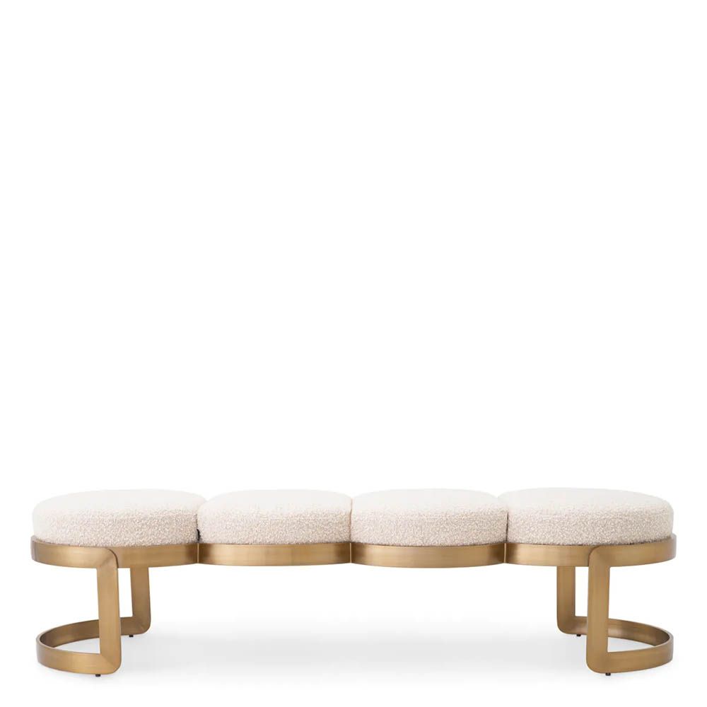 A luxury bench by Eichholtz with a boucle cream upholstery and brushed brass finish