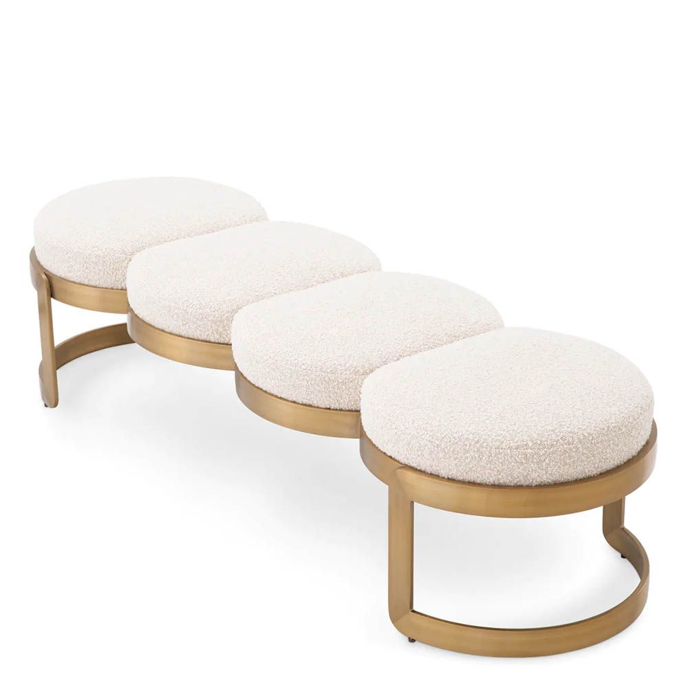A luxury bench by Eichholtz with a boucle cream upholstery and brushed brass finish