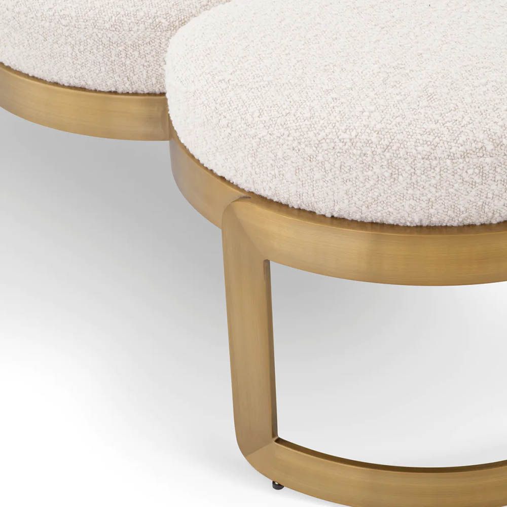 A luxury bench by Eichholtz with a boucle cream upholstery and brushed brass finish