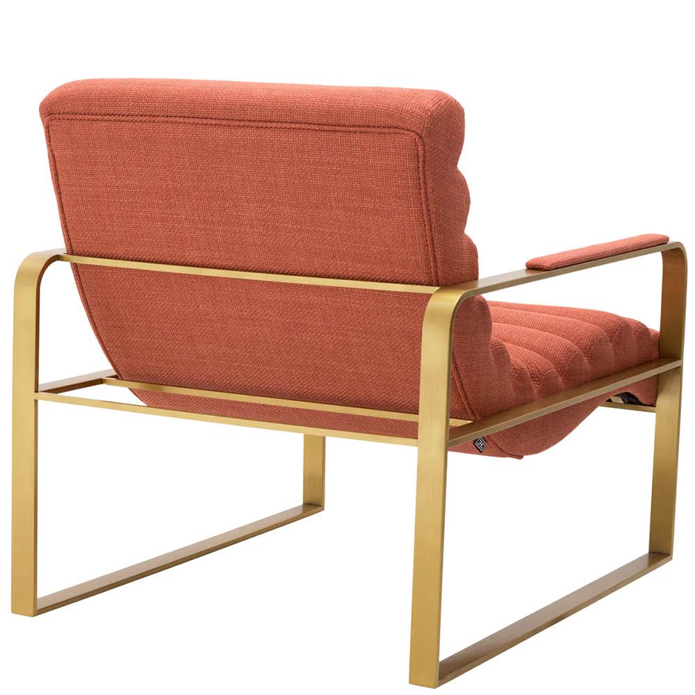 orange linen upholstered armchair with horizontal fluting and brass frame