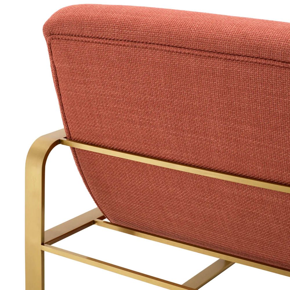 orange linen upholstered armchair with horizontal fluting and brass frame
