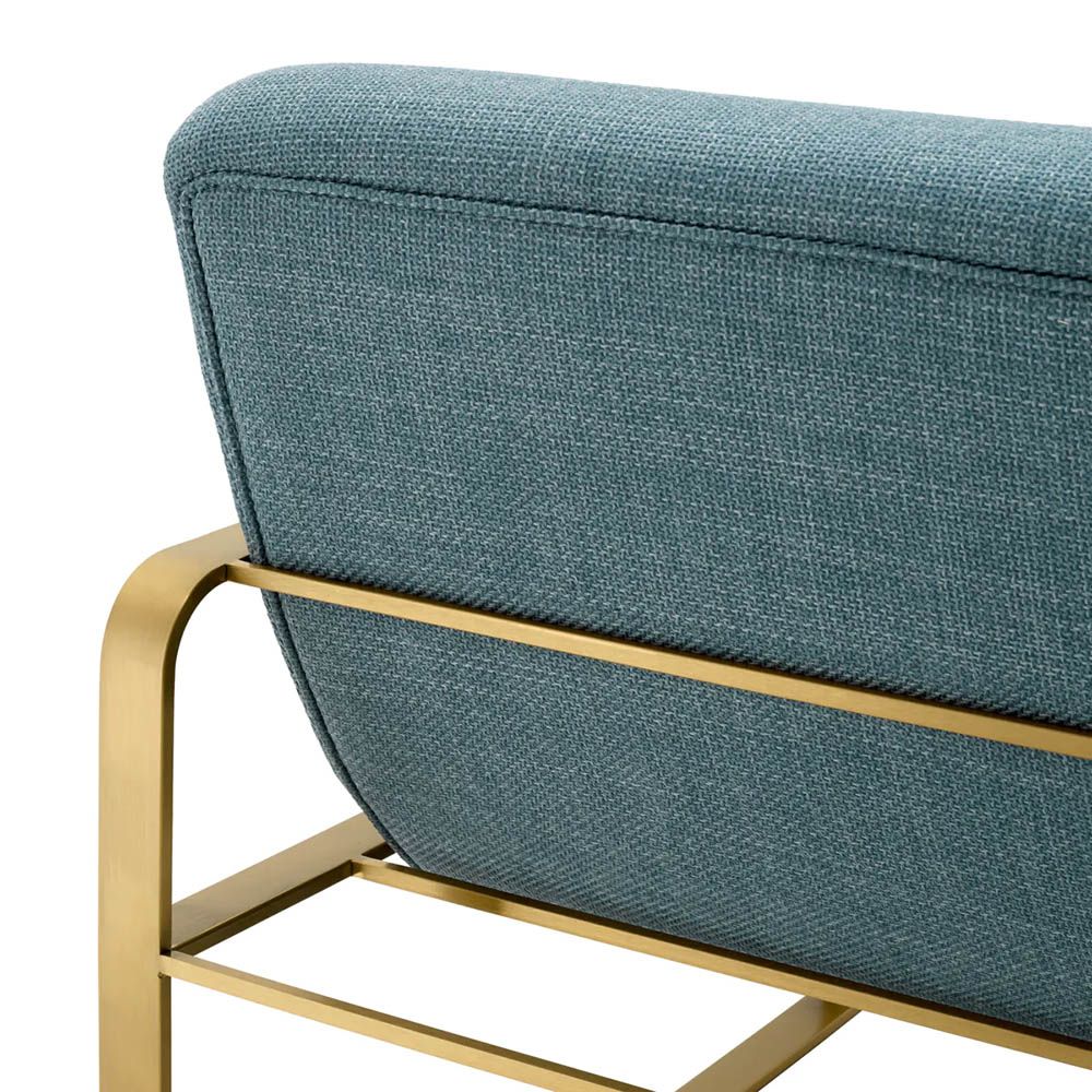 blue linen upholstered armchair with horizontal fluting and brass frame