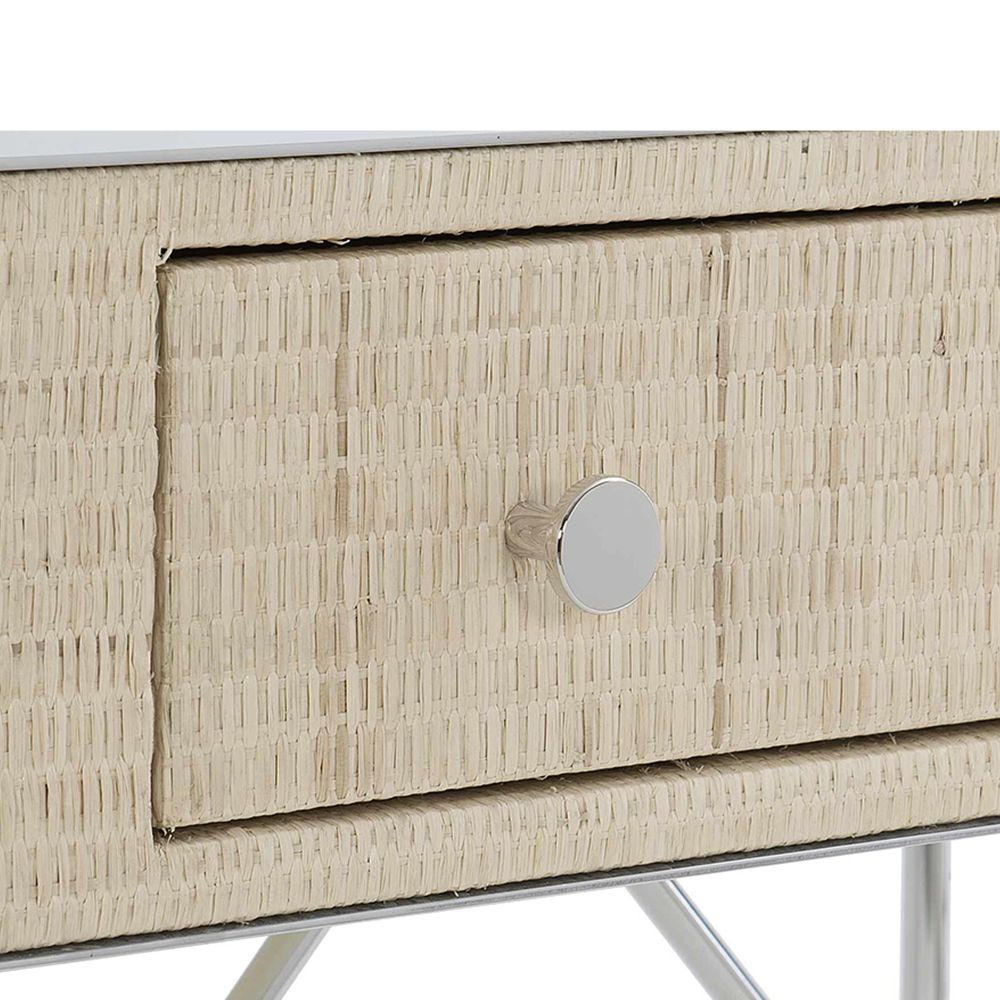 A chic and contemporary bedside table featuring a woven bleached raffia wrapped drawer box and finished with a polished stainless steel top and base