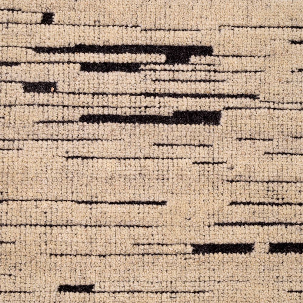 textured cream rug with black specs and a fringe