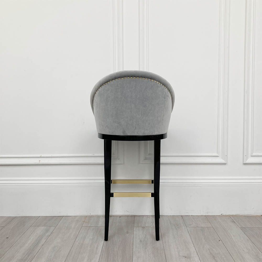 A sumptuous bar stool with a luxurious velvet upholstery and glossy lacquered legs 