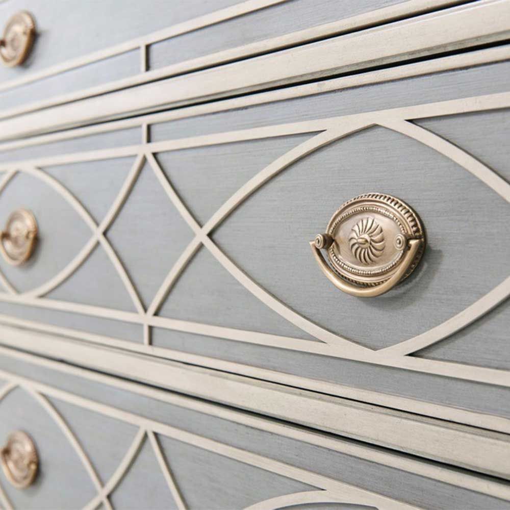 Grey chest of drawers with cream art-deco patterning and intricate brass handles