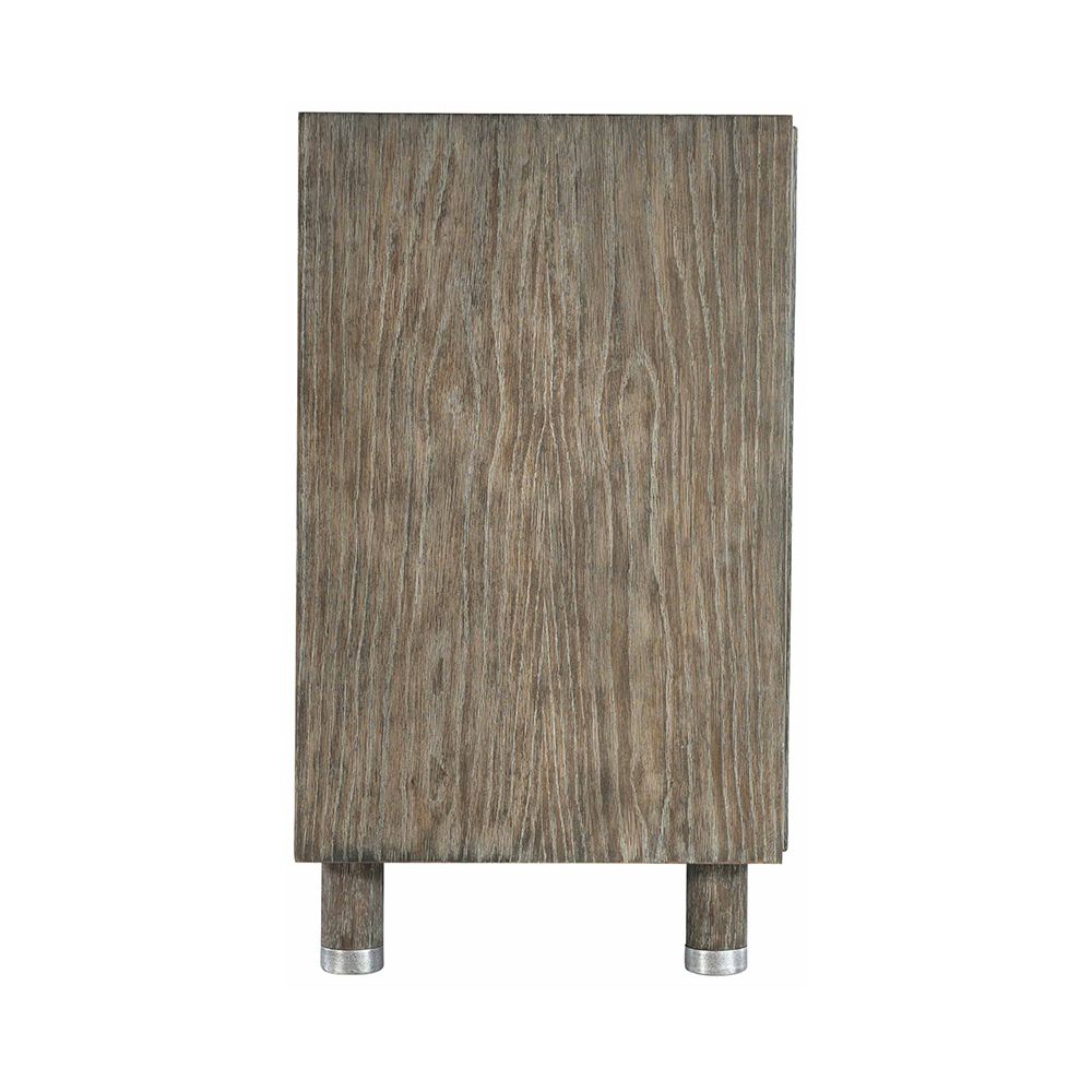 A textured wooden sideboard with four carved geometric patterned doors and finished with nickel plated aluminium legs