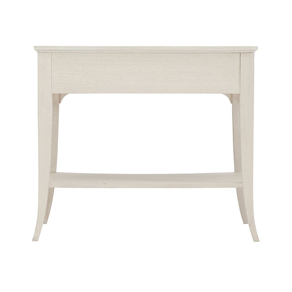 A sophisticated one-drawer bedside table with a concave shape, quartered white oak veneers, a Manor White finish and silver luster highlights