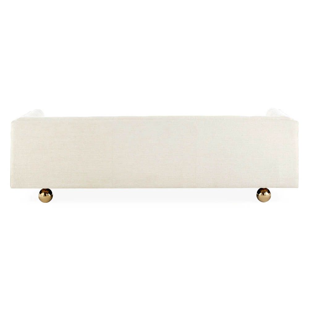 A stylish sofa by Jonathan Adler with a luxury cream upholstery and glamorous gold orb feet