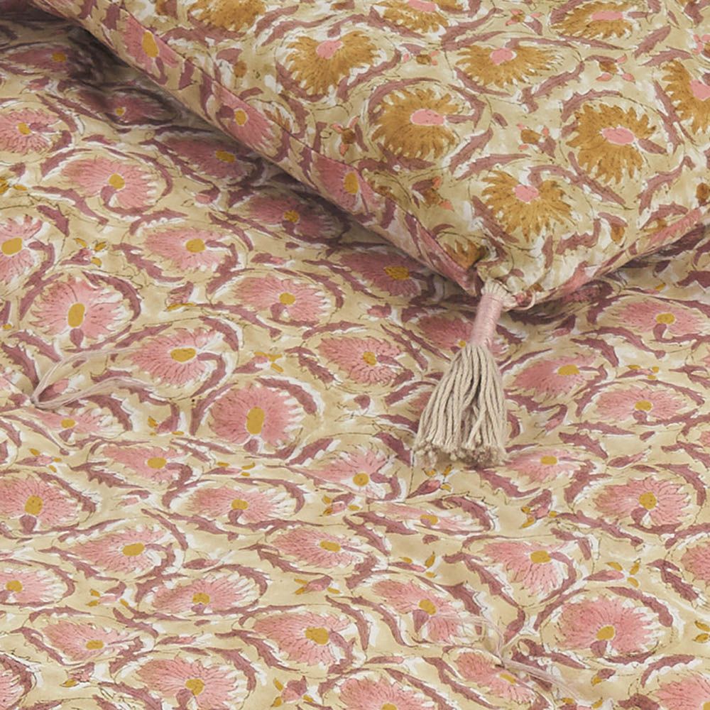 Pink and yellow patterned quilt with tassels at the corners