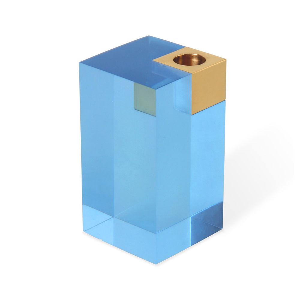 A glamorous candleholder by Jonathan Adler featuring a blue acrylic block fitted with a solid brass candleholder