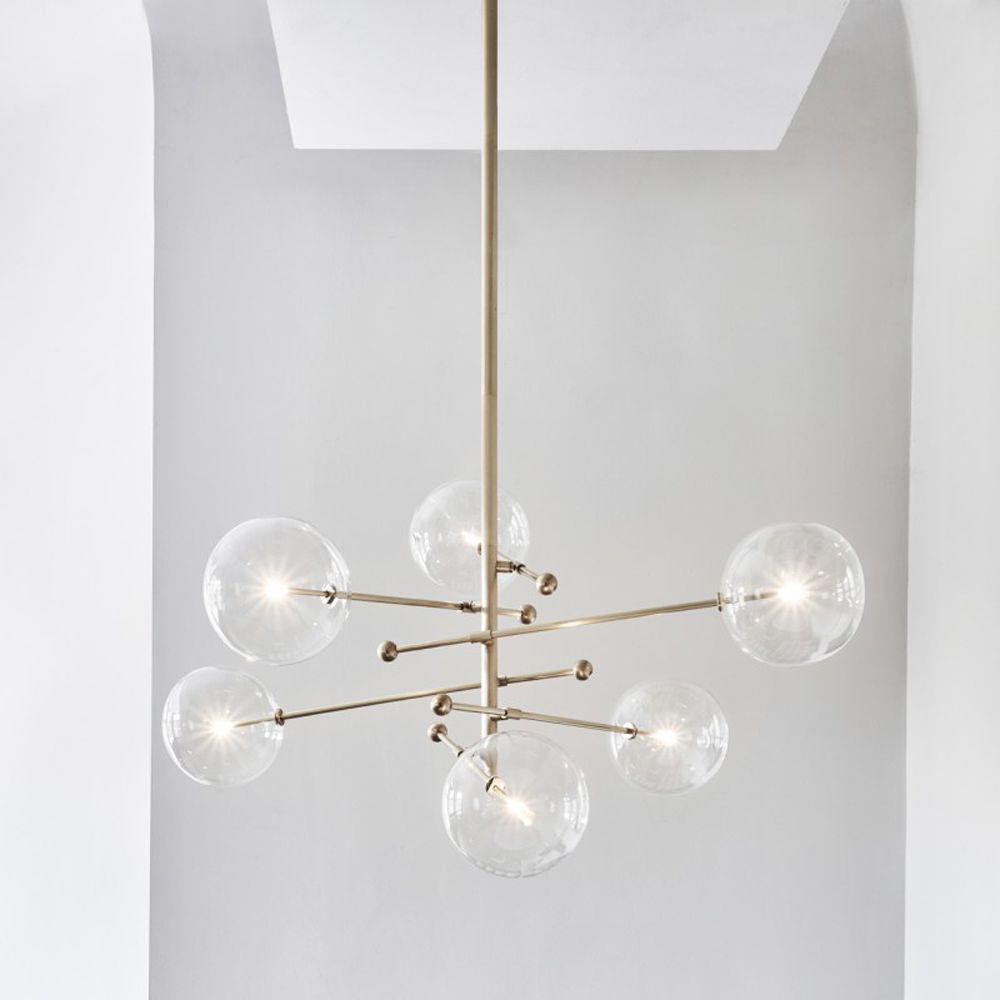Industrial style 6 arm chandelier in a natural brass finish with 6 clear glass globe bulbs