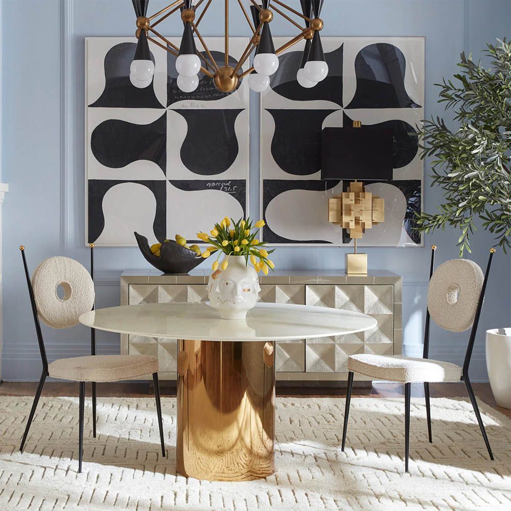 A glamorous dining table by Jonathan Adler with a brass base and marble top