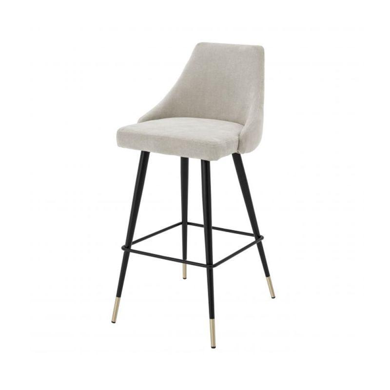 A luxurious bar stool in a sand-toned fabric with polished brass detailing