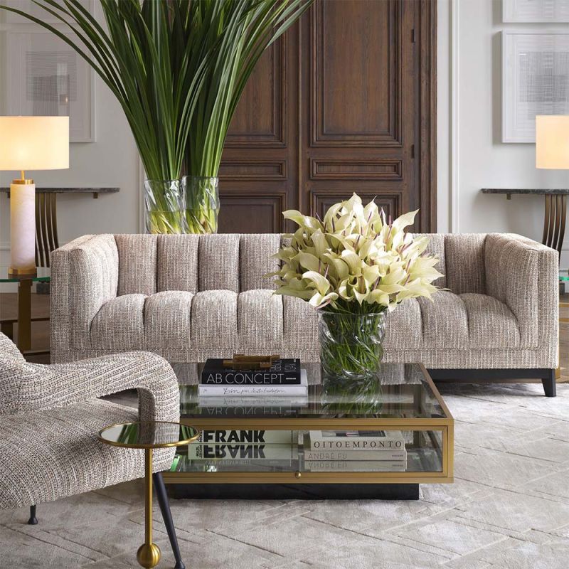 A gorgeous rustic inspired sofa upholstered in a beige fabric with black features.