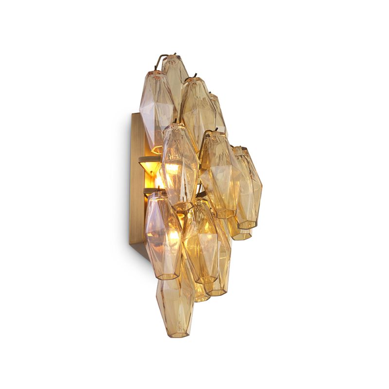 A statement wall lamp by Eichholtz with diamond-shaped, amber glass tubes and an antique brass finish