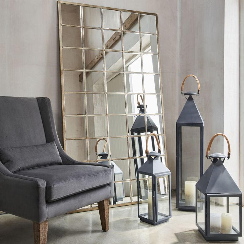 A large leaning mirror with an antiqued design featuring a bevelled mirror and champagne gold, hand-painted wood finish
