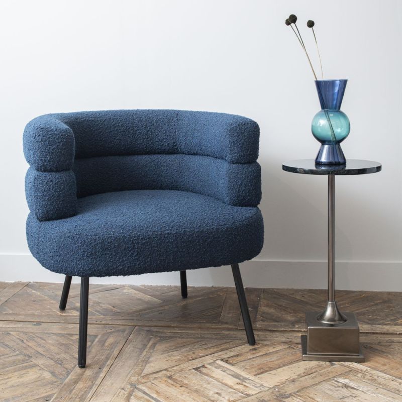 A beautiful blue bouclé upholstered armchair with a deep curved silhouette and metallic legs 