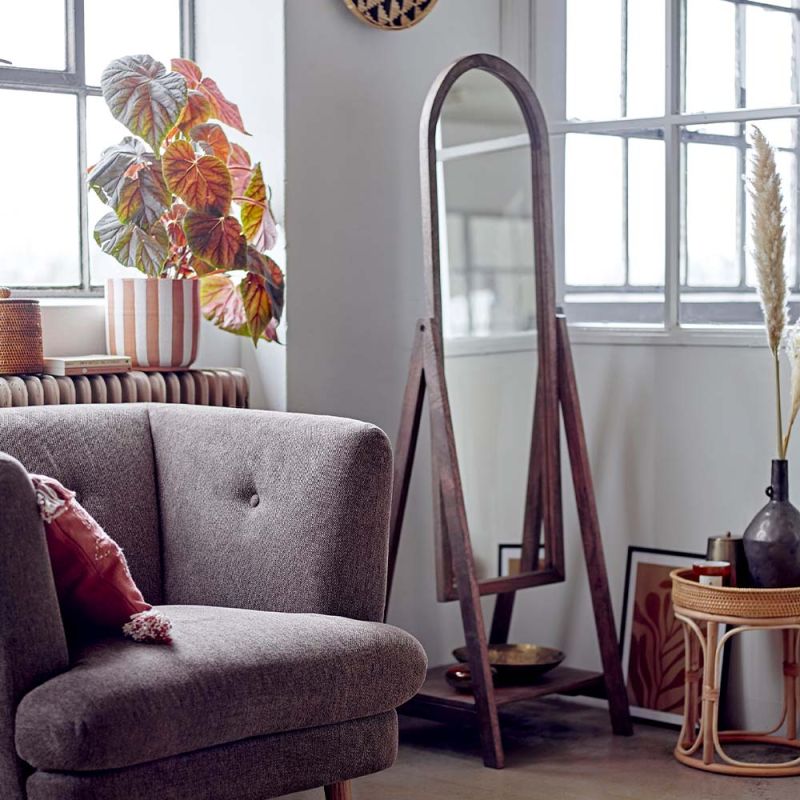 A chic standing mirror in a brown frame and a small lower shelf