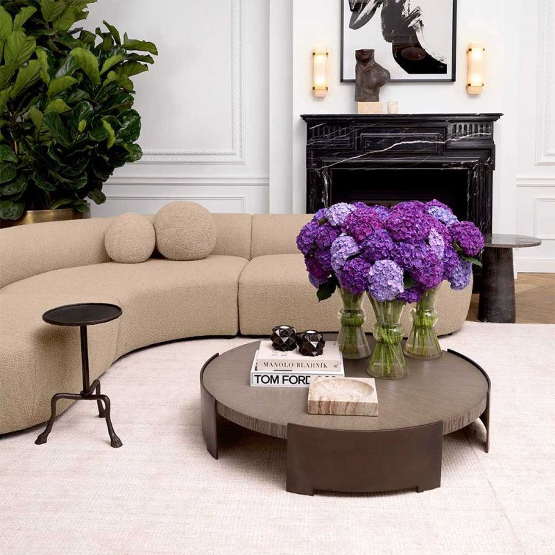 Round coffee table with wooden surface suspended between bronze legs