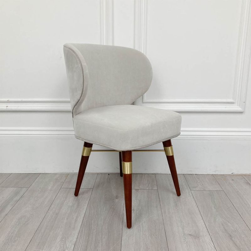 A luxurious, velvet dining chair with walnut wood and brass detailed legs.