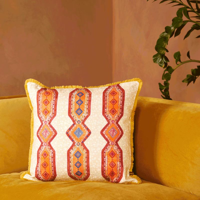 A luxury cushion by Eva Sonaike with an orange African-inspired pattern and fringing