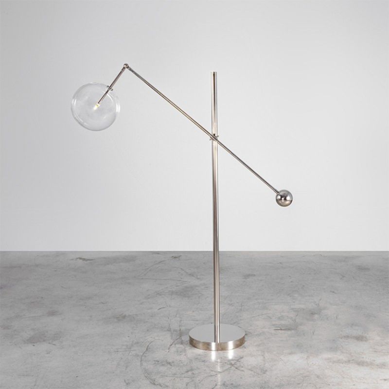 Polished nickel industrial floor lamp with angled frame and clear glass globe lampshade