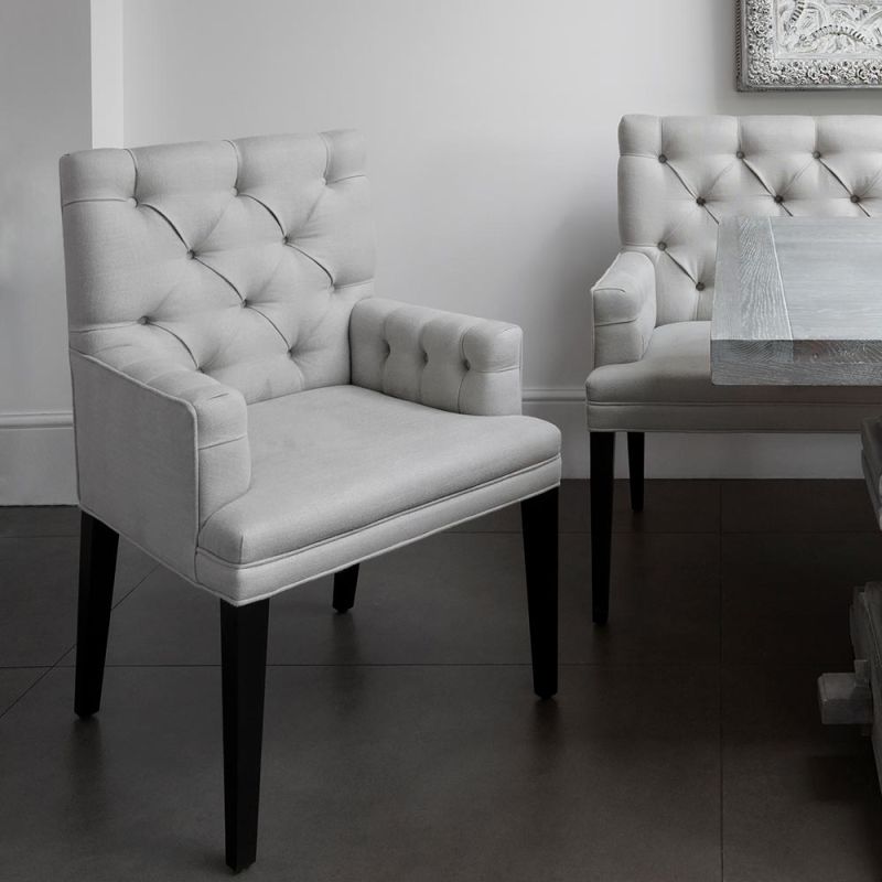 Contemporary, deep buttoned dining chair with arms and piping detail