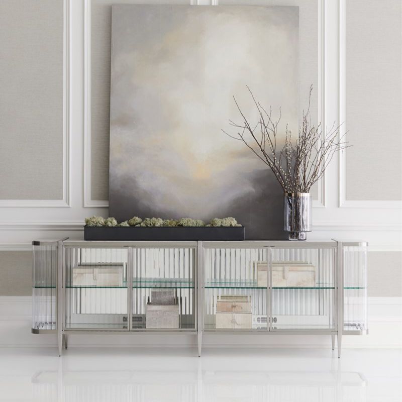 A contemporary console table by Caracole with clear, wave-effect acrylic doors and a mirrored interior