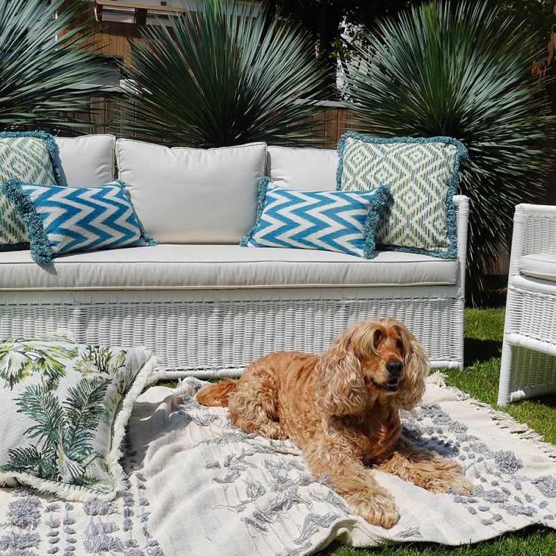 A teal, zigzag patterned cushion with matching fringe details.