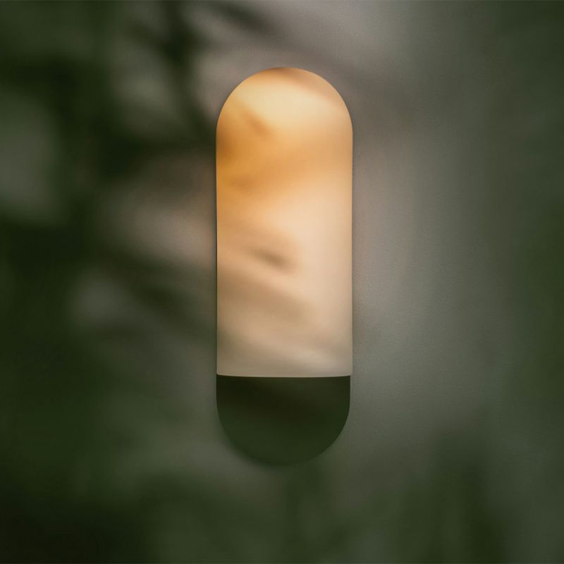 Sculpted wall sconce with a forest green fixture and a frosted glass shade