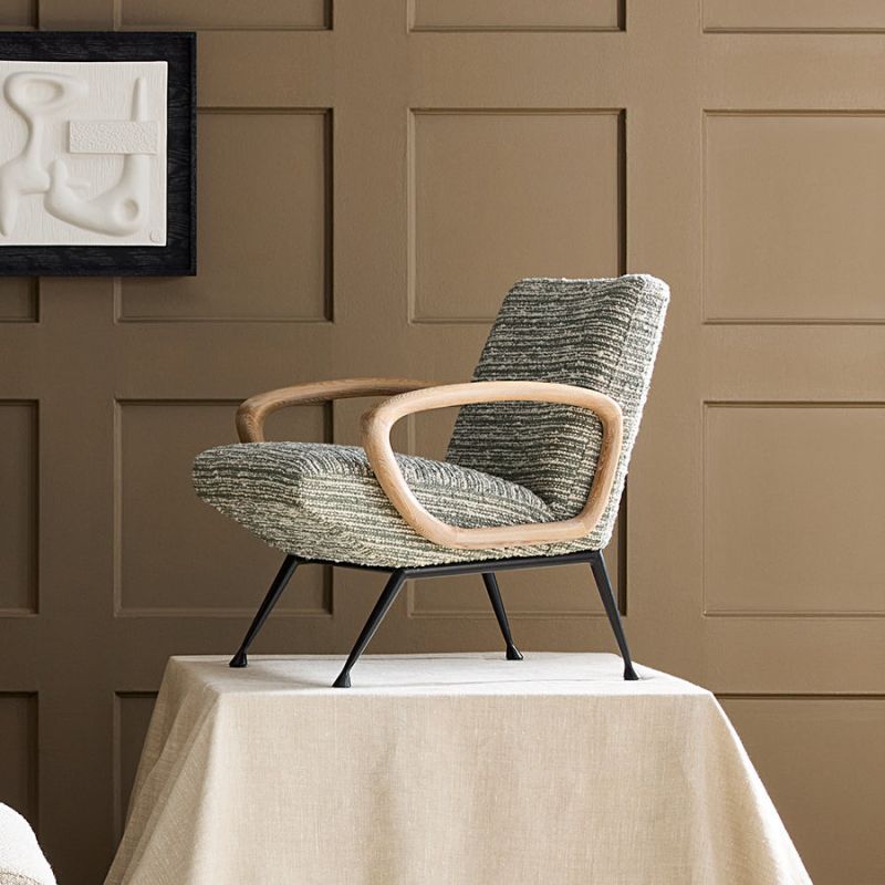 The Gainsbourg Lounge Chair is a vintage-inspired piece with a cushy seat, cerused ash wood arms, and blackened metal legs, perfect for pairing with a sofa.