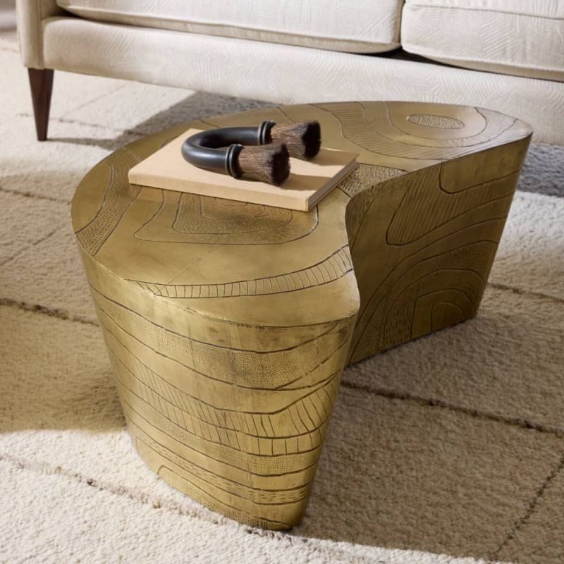 Coffee table in natural, curved silhouette in antique brass finish.
