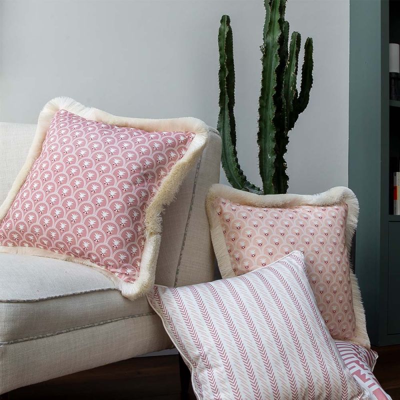 A pink fringed cushion with art deco inspired floral motifs