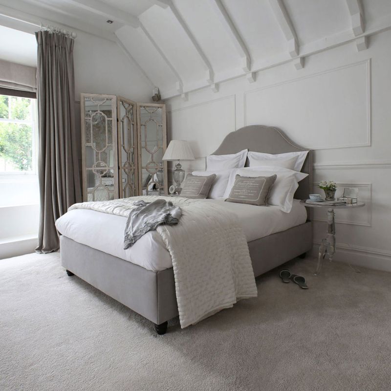 Designer bed with an elegant, curved headboard and stud detailing 