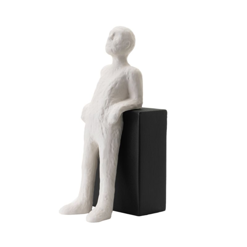 Ceramic sculpture of a man leaning casually against a black block 