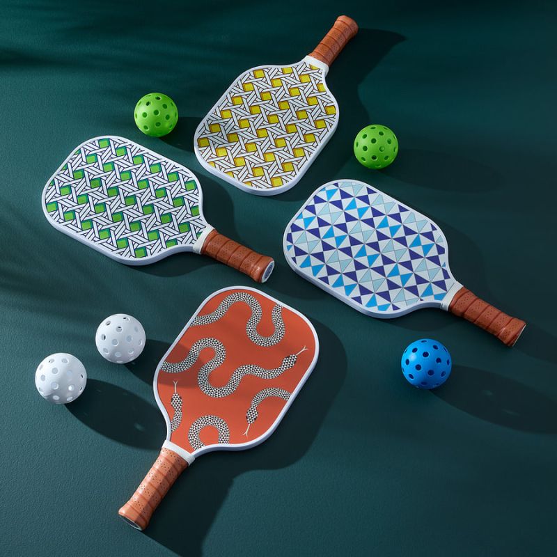 A stylish pickleball set with serpent-printed paddles, leather-wrapped handles, and a chic retro design, complete with two balls.