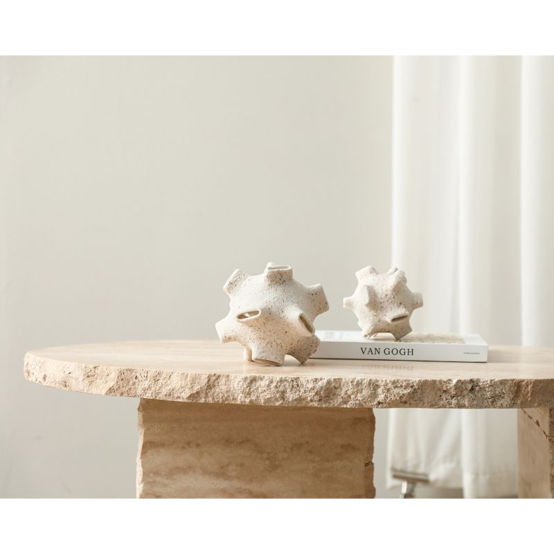 White sculpture with terracotta-coloured speckles and narrow craters